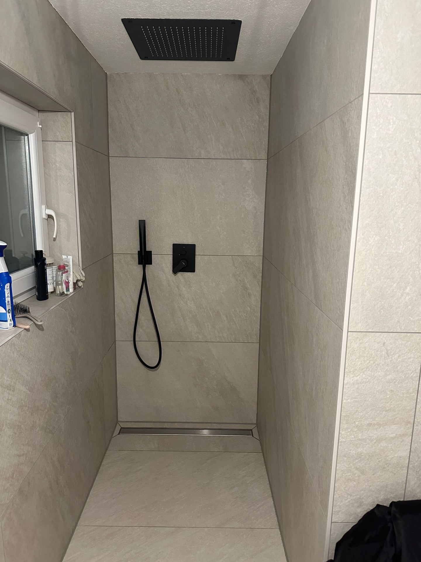 Bodengleiche Dusche mit schwarzen Armaturen nach der Sanierung